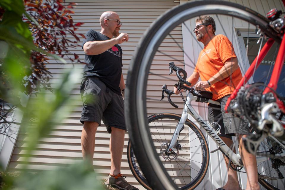 Neil Mullikin, 46, of Georgia, coordinator of the Fuller Center Bike Adventure cyclists, speaks with Rolff Christensen, 63, of California, as they fix a fellow member's bike at Milan Free Methodist Church during a rest stop in Milan on Tuesday, July 5, 2022.