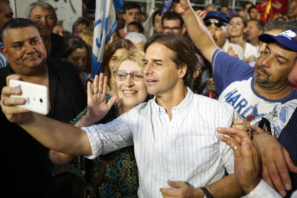 El candidato presidencial del Partido Nacional, Luis Lacalle Pou, se toma una selfie con simpatizantes durante su acto de cierre de campaña en Las Piedras, Uruguay, el miércoles 20 de noviembre de 2019. (AP Foto/Matilde Campodonico)