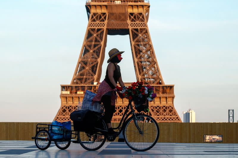 FILE PHOTO: A woman, wearing a mask, rides her bicycle near the Eiffel tower at Trocadero square in Paris