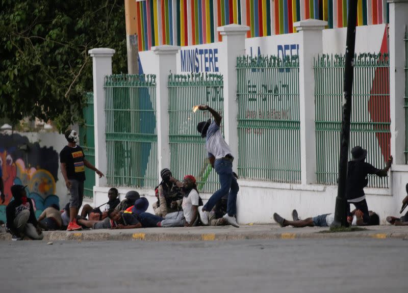 A protester throws a molotov cocktail towards the Carnival stand of the Ministry of Defence in Champ de Mars, Port-au-Prince