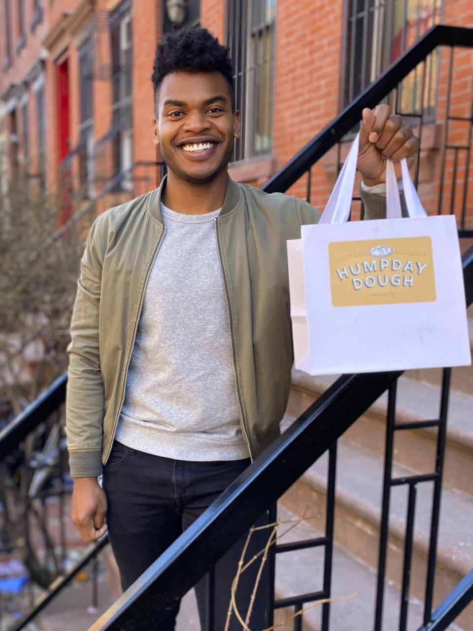 Broadway performer Max Kumangai holds a bag promoting his company Humpday Dough in New York. The triple threat from the musical “Jagged Little Pill” has leaned into a fourth skill as the pandemic marches on: baking and selling his own sourdough. (Michael Lowney/Humpday Dough via AP)