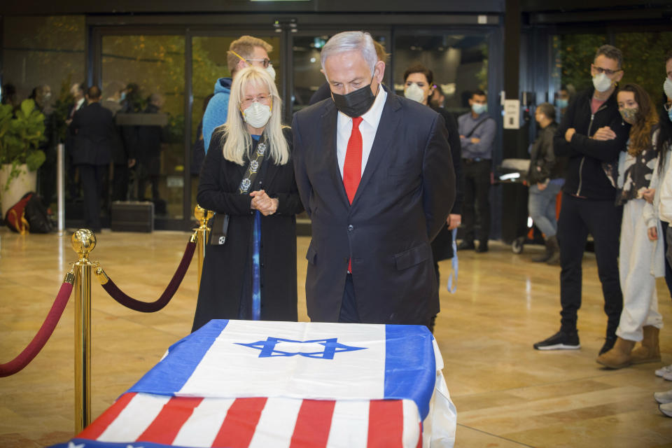 Israeli Prime Minister Benjamin Netanyahu stands before the casket of Sheldon Adelson, with his wife, Miriam Adelson, upon arrival to Ben Gurion Airport, near the city of Lod, Israel, Thursday, Jan. 14, 2021. Adelson, the billionaire mogul and power broker who built a casino empire spanning from Las Vegas to China and became a singular force in domestic and international politics has died after a long illness, his wife said Tuesday, Jan. 12, 2021. (Ami Shooman, Israel Hayom/ Pool Photo via AP)