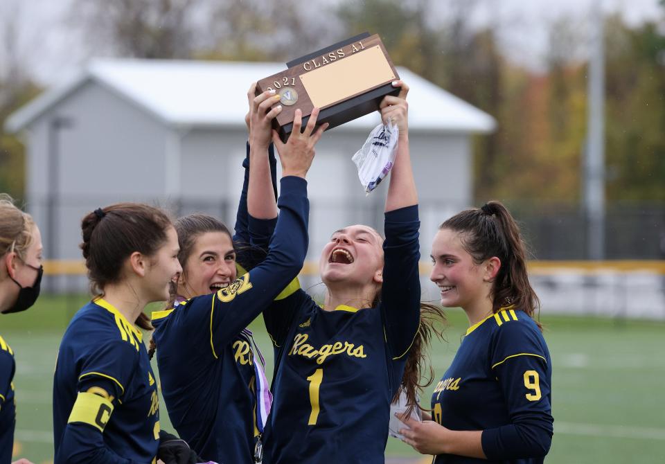 Spencerport's Lily Brongo holds up the Class A title trophy after beating Brighton 5-2.