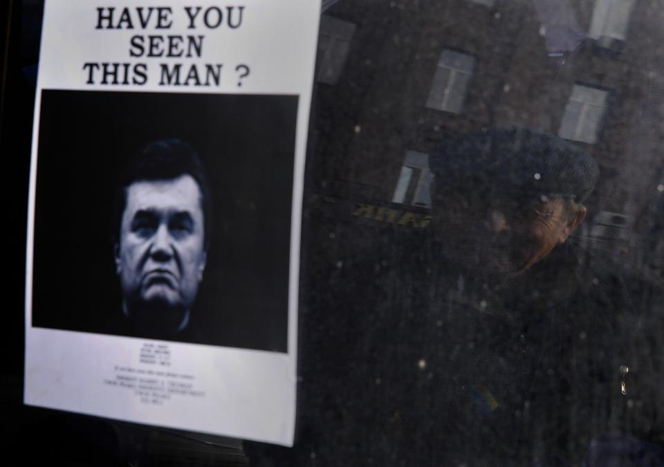 A elderly man looks at a "Wanted" notice for fugitive Ukrainian President Victor Yanukovich in Independence Square in Kiev