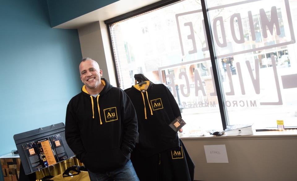 Brandon Navin, founder of The Artist's Umbrella, sets up his pop-up market in spring 2022 at the Middle Village Micro Market in downtown Lansing.