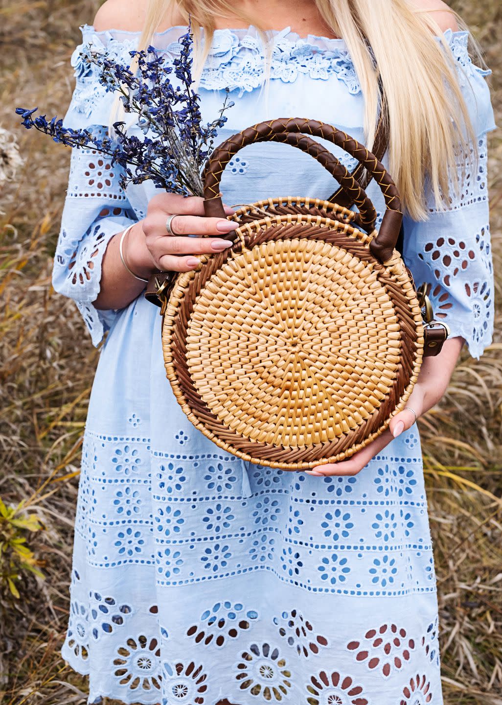 woman with trendy nude rattan round bag walking outdoors village landscaped, fall season