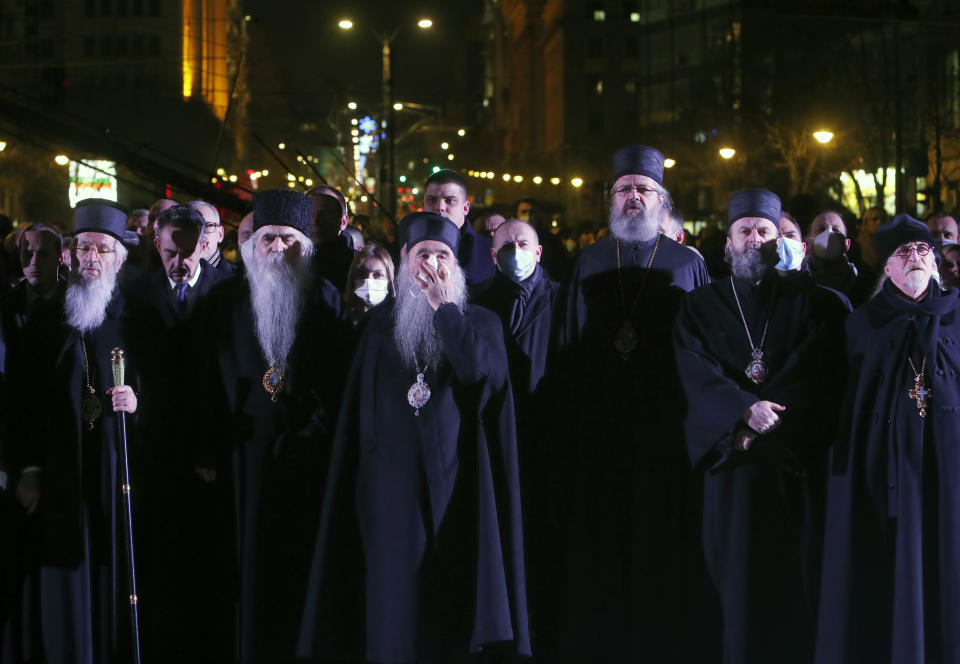 Priests watch a 23-meter-high, 70-ton bronze sculpture of the legendary founder of the Serbian state, Stefan Nemanja, during the unveiling ceremony in Belgrade, Serbia, Wednesday, Jan. 27, 2021. President Aleksandar Vucic's allies say the bronze sculpture of Stefan Nemanja will be a new landmark of the Serbian capital. Opponents think the monument is a megalomaniac and pricy token of Vucic's populist and autocratic rule that should be removed. (AP Photo/Darko Vojinovic)