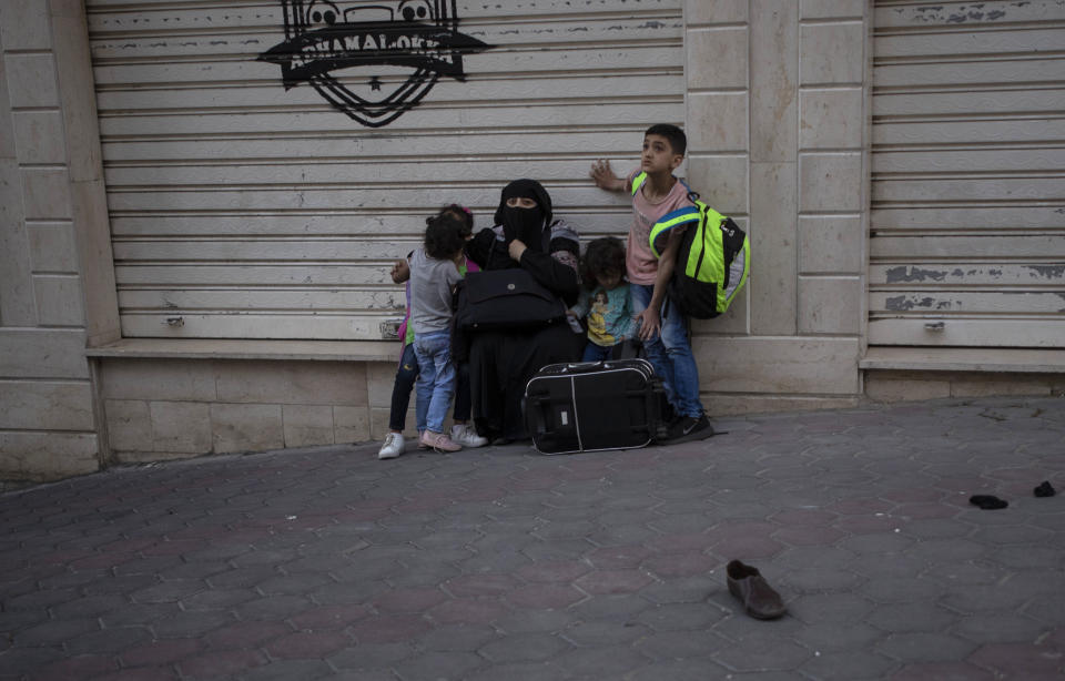 A Palestinian family sit on the street side after they were evacuated from a building following Israeli airstrikes on Gaza City, Wednesday, May 12, 2021. Rockets streamed out of Gaza and Israel pounded the territory with airstrikes early Wednesday as the most severe outbreak of violence since the 2014 war took on many of the hallmarks of that devastating 50-day conflict, with no endgame in sight. (AP Photo/Khalil Hamra)