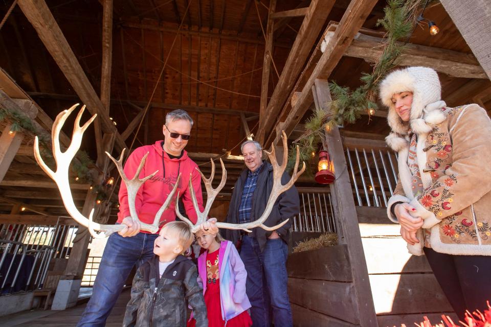 Alex Perzyk holds reindeer antlers to the head of his 2-year-old son Nico Perzyk while his 5-year-old daughter Alyse Perzyk looks on. The family, from Pontiac, Mich., was visiting Grandpa Tiny's Farm in Frankenmuth, Mich. on November 19, 2023, to see live reindeer. The owner of the farm, Wendy Winkel, pictured at right, collected the antlers from the reindeer named Blue after he shed them in 2022. Looking on from behind the Perzyk family is the children's grandfather Ronald Rippon of Lake Orion, Mich.