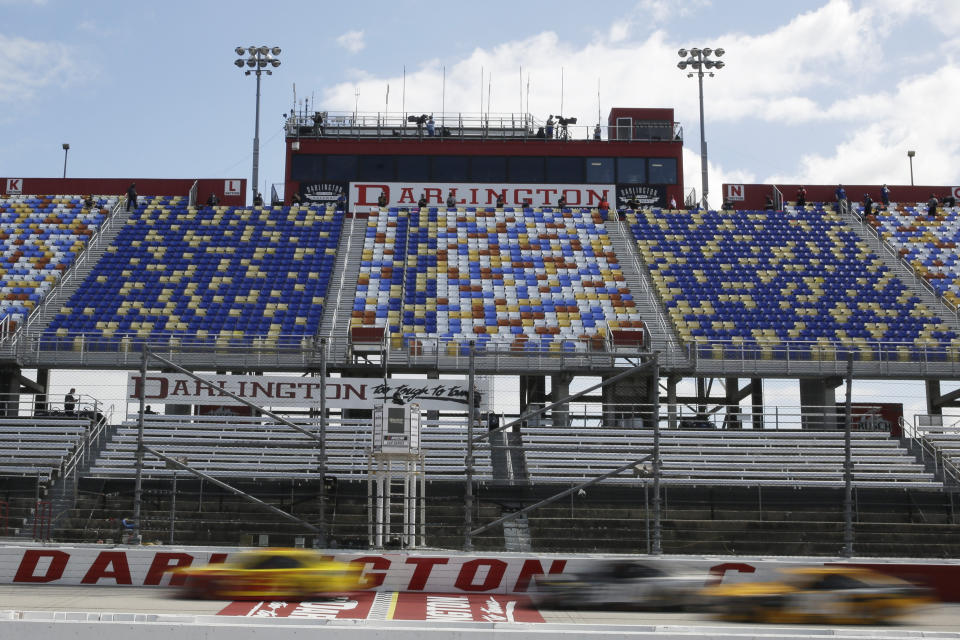 Cars pass by empty seats during the NASCAR Cup Series auto race Sunday, May 17, 2020, in Darlington, S.C. (AP Photo/Brynn Anderson)