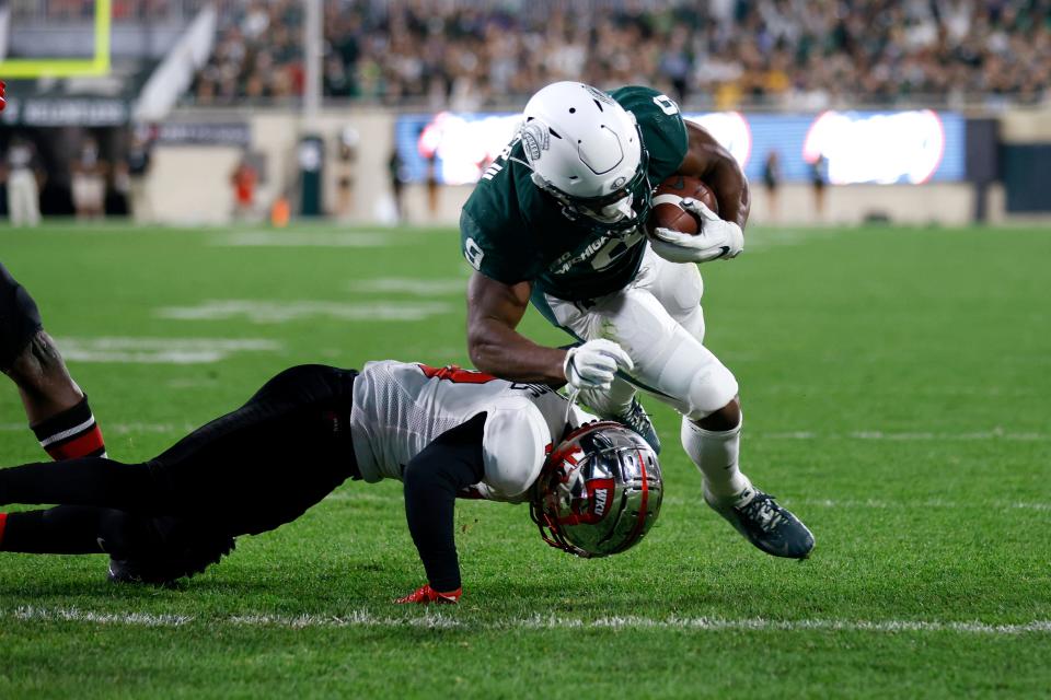 Michigan State's Kenneth Walker III, top, dives over Western Kentucky's Miguel Edwards for a touchdown during the first quarter of an NCAA college football game, Saturday, Oct. 2, 2021, in East Lansing, Mich.