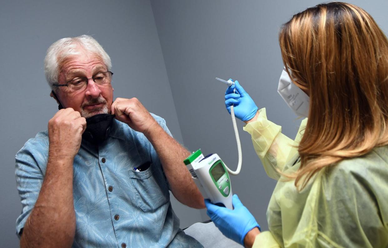 <span class="caption">Tony Potts, a 69-year-old retiree, removes his face mask for a temperature check just before receiving his first injection in a phase 3 COVID-19 vaccine clinical trial sponsored by Moderna. Potts is one of 30,000 participants in the Moderna trial. </span> <span class="attribution"><a class="link " href="https://www.gettyimages.com/detail/news-photo/tony-potts-a-69-year-old-retiree-living-in-ormond-beach-news-photo/1227916339?adppopup=true" rel="nofollow noopener" target="_blank" data-ylk="slk:Paul Hennessy/NurPhoto via Getty ImageS;elm:context_link;itc:0;sec:content-canvas">Paul Hennessy/NurPhoto via Getty ImageS</a></span>