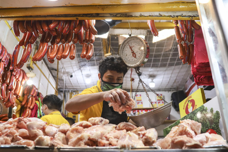 An employee weighs an order of chicken at a popular market in Managua, Nicaragua, Tuesday, April 7, 2020. Restaurants are empty, there's little traffic in the streets and beach tourists are sparse headed into Holy Week despite the government's encouragement for Nicaraguans to go about their normal lives. (AP Photo/Alfredo Zuniga)