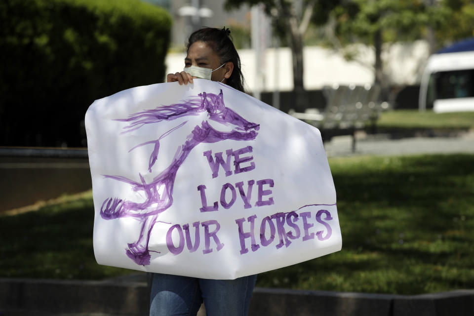 A horse racing supporter stands outside the Board of Supervisors building to protest the closing of Santa Anita Park as part to the state's stay-at-home measures amid the COVID-19 pandemic Tuesday, April 28, 2020, in Los Angeles. (AP Photo/Marcio Jose Sanchez)