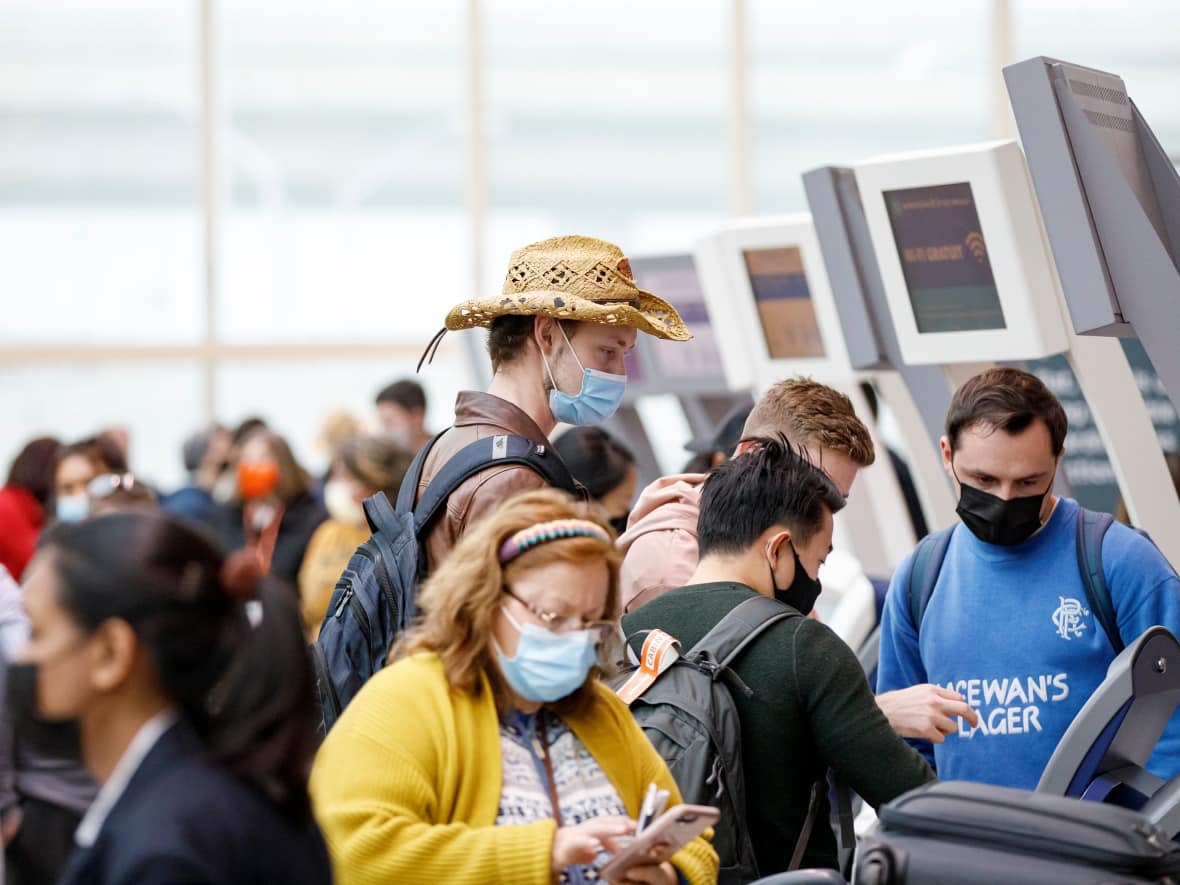 Travellers walk through Pearson International Airport in Toronto in December 2021. One Ottawa travel expert says it's not a bad time to travel — but if you do, you should plan ahead to avoid complications down the road. (Evan Mitsui/CBC - image credit)