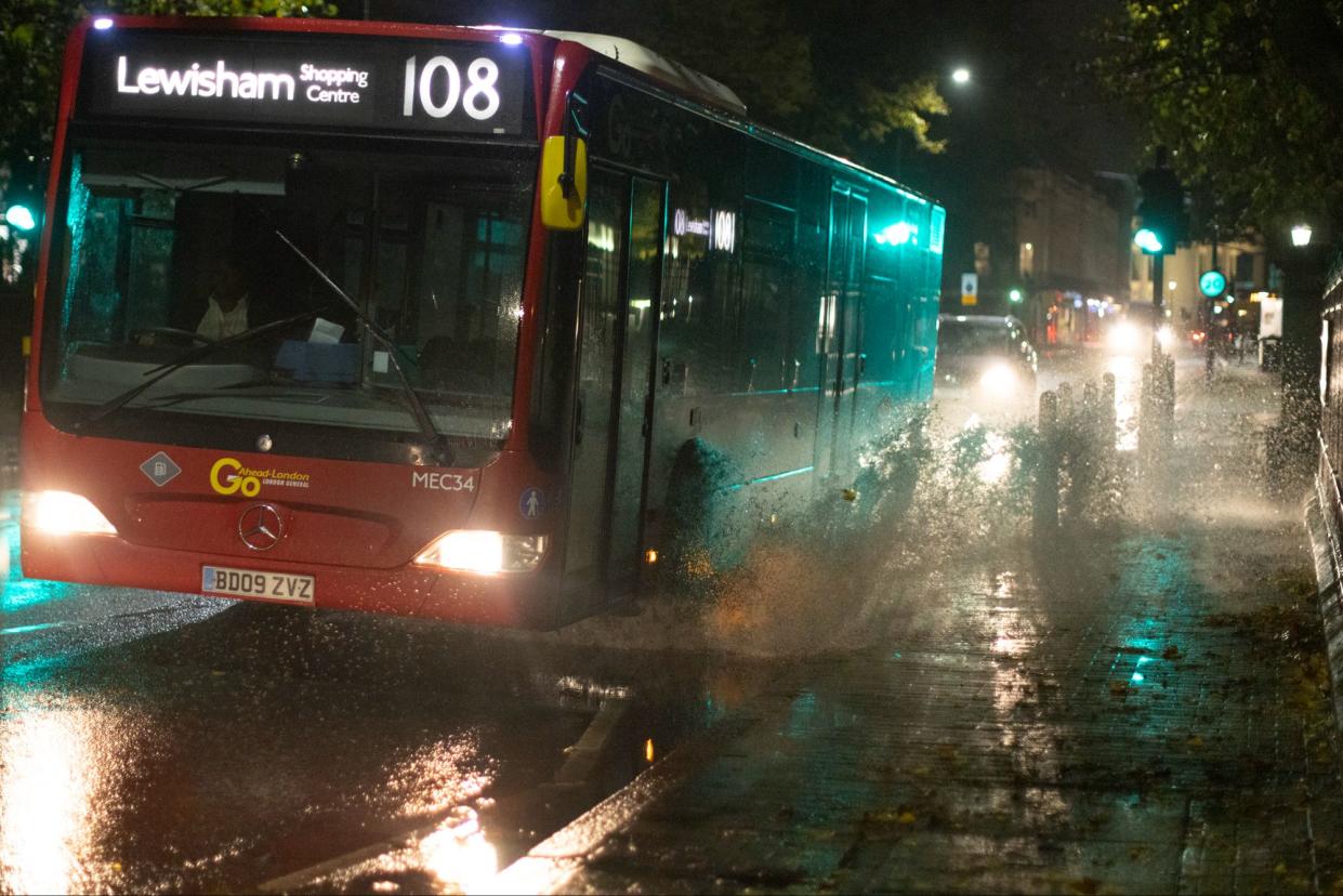 Vehicles create a large splash as they are driven through substantial puddles in Greenwich (George Cracknell Wright)