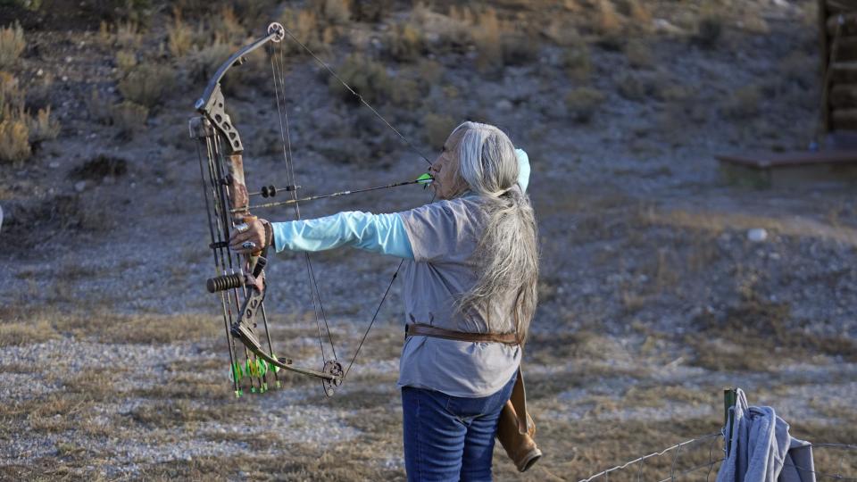 Delaine Spilsbury, an Ely Shoshone elder, shoots an arrow in her backyard on Nov. 10, 2023, near McGill, Nev. As a kid, her family lived off the land, which inspired her to become a bow hunter and compete in archery. (AP Photo/Rick Bowmer)