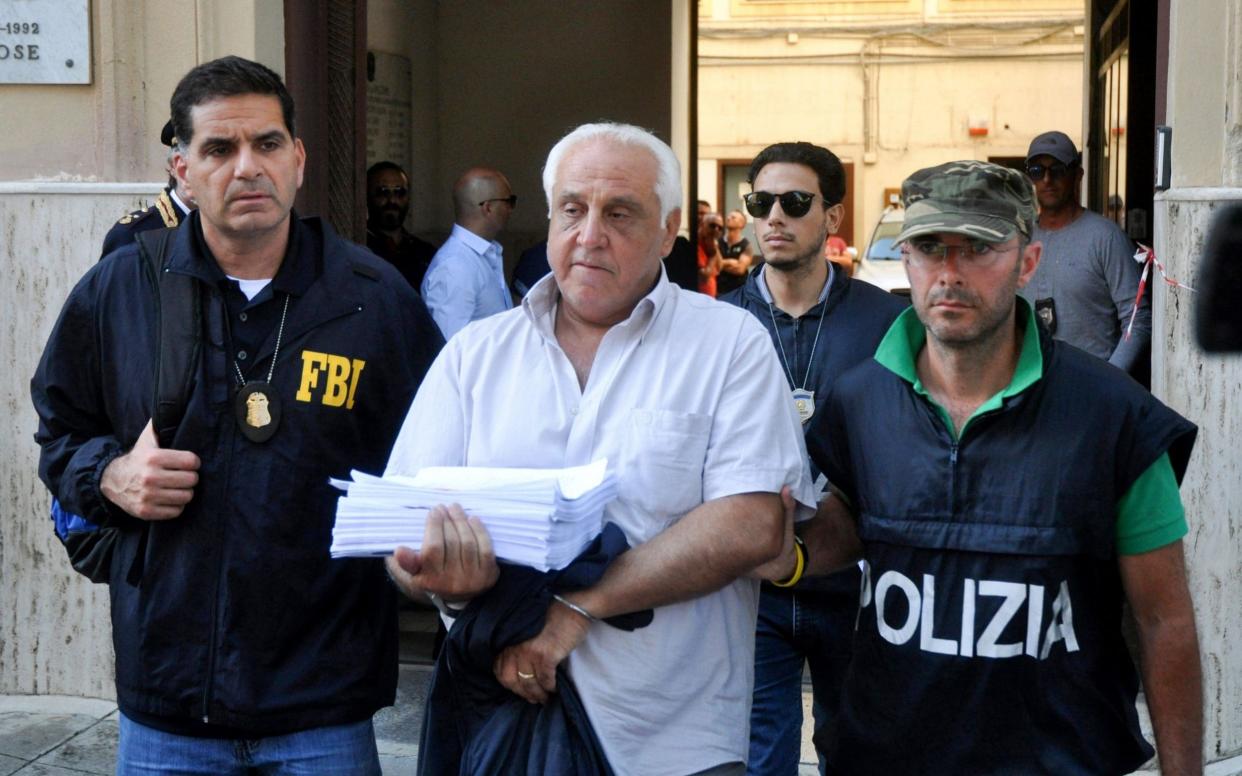 An FBI officer and an Italian police officer escort a suspect named Tommaso Inzerillo after he was arrested in Palermo during a joint operation called 'New Connection'  - AFP