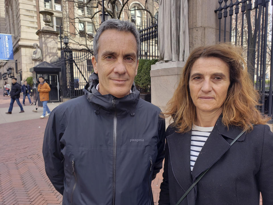 In this March 11, 2020 photo, Gianmarco de Felice and his wife, Annaelisa Lugini pose for a photo outside Columbia University in New York City. Italians in New York are worried for loved ones in Italy who are living under a nationwide lockdown to stem the spread of the new coronavirus. De Felice is in New York for a few months doing research. Lugini has been visiting and had been planning to return to Italy earlier this week, but decided to stay to avoid the lockdown. For most people, the new coronavirus causes only mild or moderate symptoms. For some it can cause more severe illness. (AP Photo/Juan Carlos Velasquez)