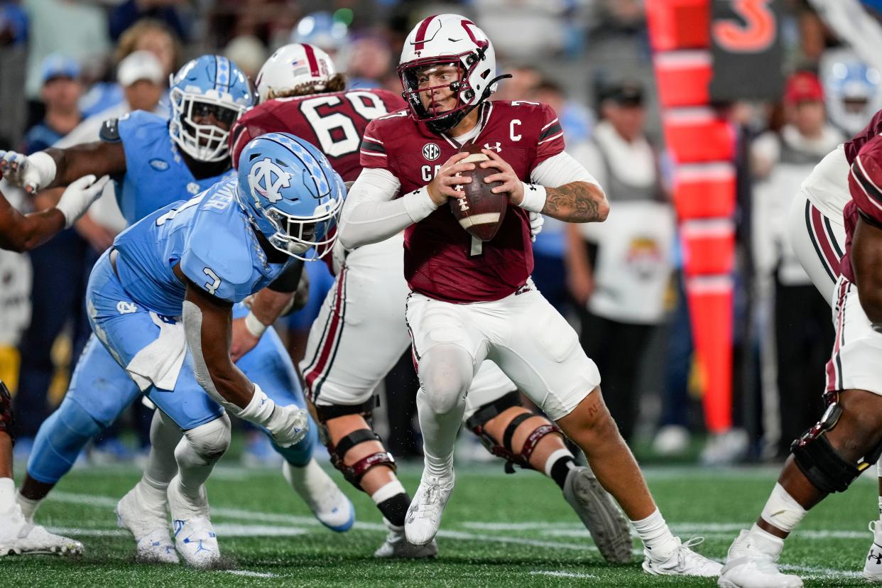 South Carolina Gamecocks quarterback Spencer Rattler (7) tries to elude North Carolina Tar Heels linebacker Amari Gainer (3) during the second half at Bank of America Stadium.