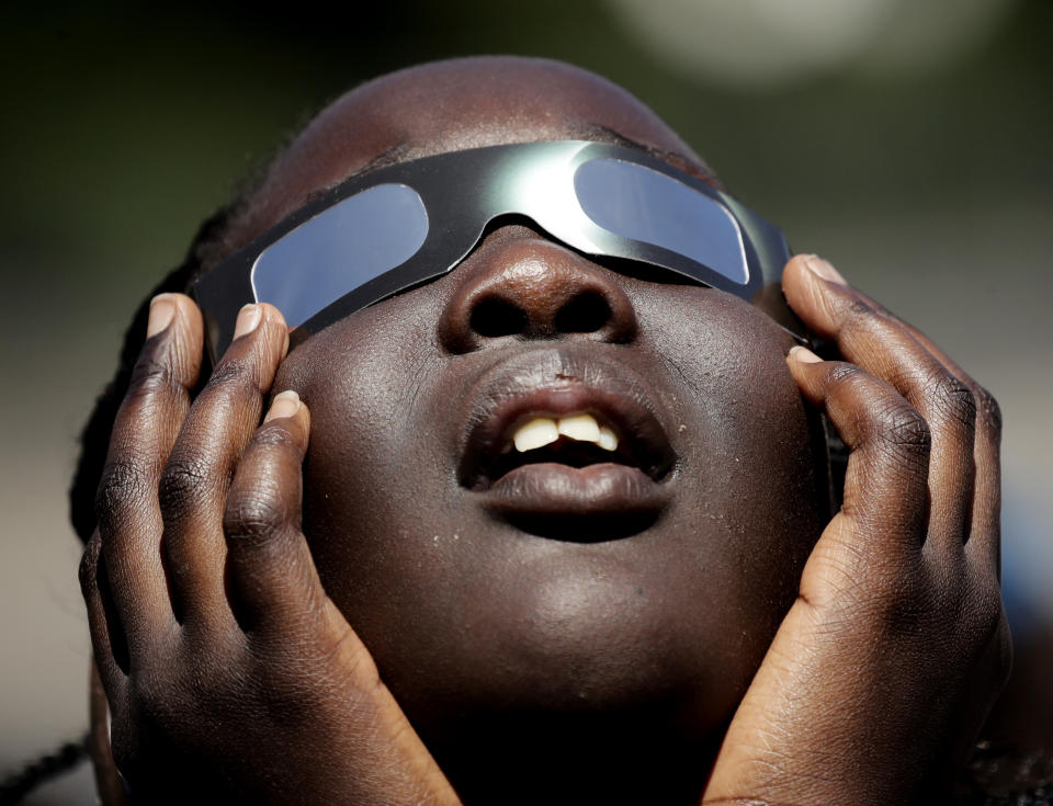 FILE - In this photo taken Friday, Aug. 18, 2017, Poureal Long, a fourth grader at Clardy Elementary School in Kansas City, Mo., practices the proper use of eclipse glasses in anticipation of Monday's solar eclipse. More and more businesses are taking advantage of the total solar eclipse set to dim skies across North America on Monday, April 8, 2024. In the snacks department alone, Krispy Kreme is teaming up with Oreo to sell a limited doughnut-cookie creation. Sonic Drive-In is selling a “Blackout Slush Float.” (AP Photo/Charlie Riedel, File)