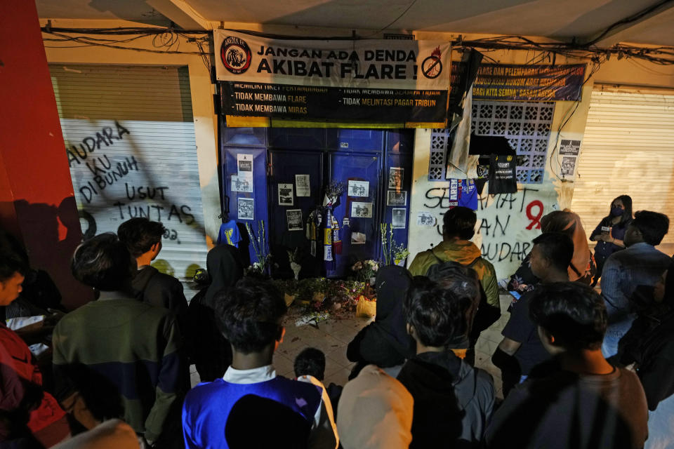 People prays in front of gate 13 at the Kanjuruhan Stadium in Malang, Indonesia, Tuesday, Oct. 4, 2022. Police said Tuesday that the gates at the soccer stadium where police fired tear gas and set off a deadly crush were too small and could only accommodate two at a time when hundreds were trying to escape. (AP Photo/Achmad Ibrahim)