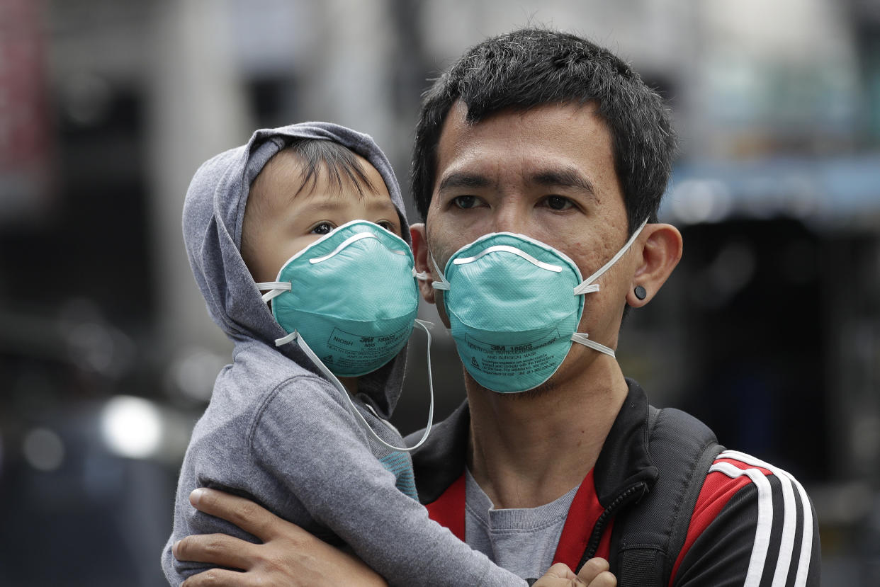 A man and a child wear protective masks in Manila, Philippines, Wednesday Feb. 5, 2020. The Philippines precautionary measures remain tight around the country from the coronavirus. (AP Photo/Aaron Favila)