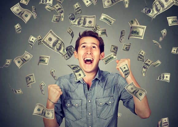 Smiling young man surrounded by floating bills