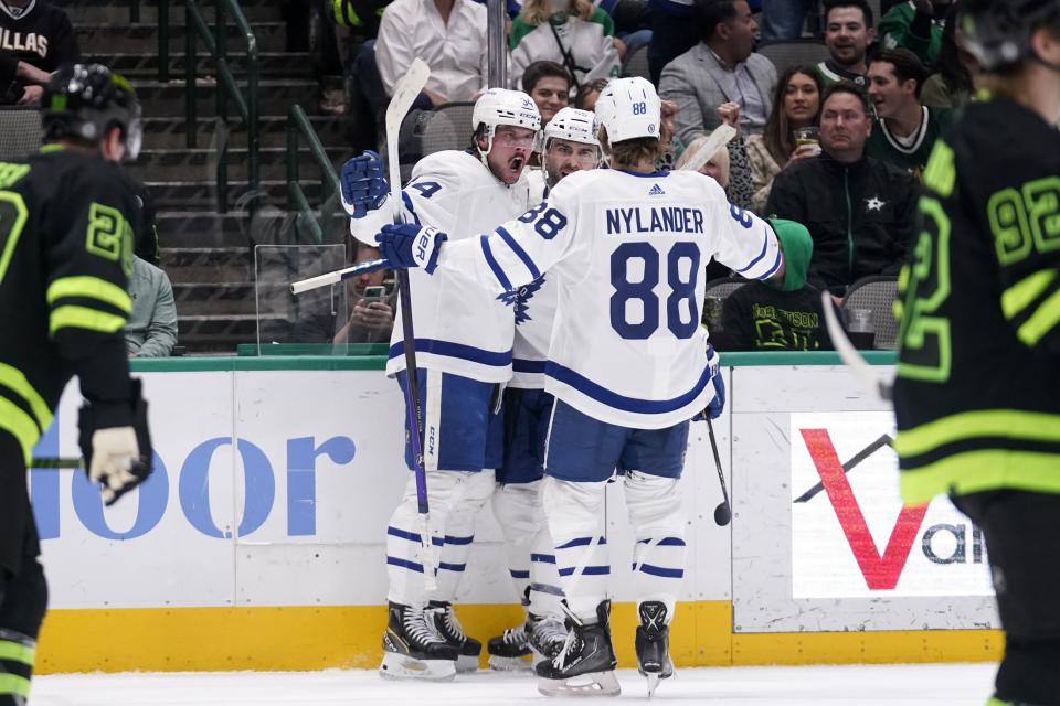 Toronto Maple Leafs center Auston Matthews, left, William Nylander (88) and Mark Giordano celebrate a goal scored by Matthews during the second period of the team's NHL hockey game against the Dallas Stars, Thursday, April 7, 2022, in Dallas. The goal was Matthews' 55th of the season. (AP Photo/Tony Gutierrez)