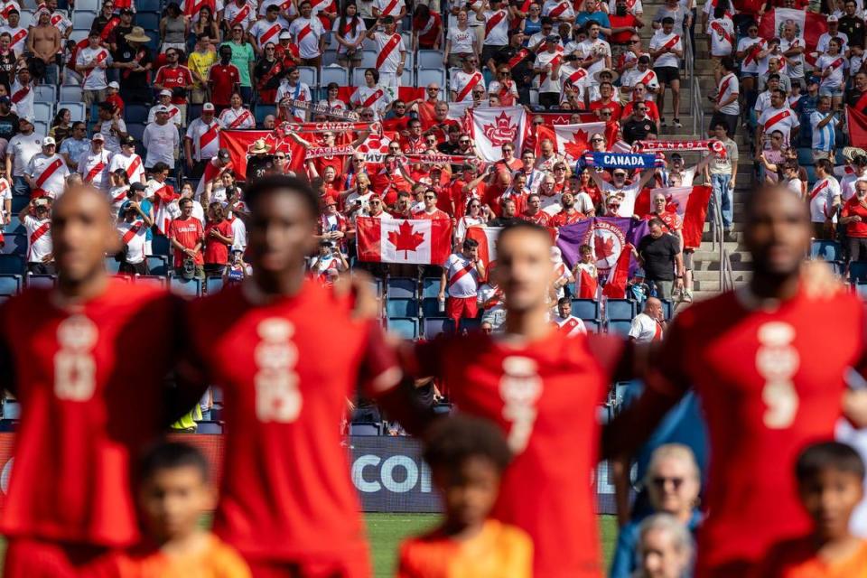 Canada fans hold up scarves and flags while singing along to Canada’s national anthem before the start of a Copa America match against Peru.