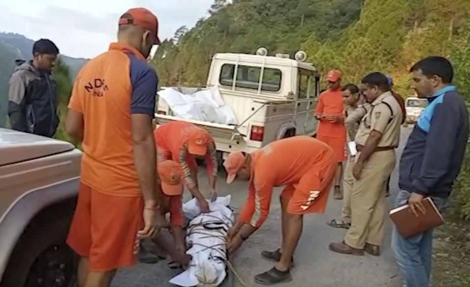 In this grab made from video provided by KK Productions, rescuers untie the body of passenger after it was pulled out from a bus that fell into a gorge in Pauri district in the northern state of Uttarakhand, India, Wednesday, Oct. 5, 2022. A bus in northern India plunged into a gorge, leaving at least 25 dead and 20 others injured, officials said. (KK Productions via AP)