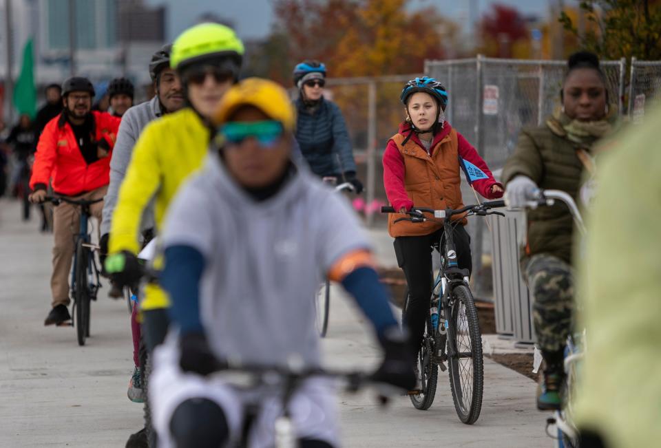 Dozens of cyclists bike next to the riverfront during the Uniroyal Promenade ribbon-cutting ceremony on Detroit's Riverwalk in Detroit on Saturday, Oct. 21, 2023. The new Uniroyal Promenade completes the 3.5 mile-long Riverwalk and provides access to Belle Isle.