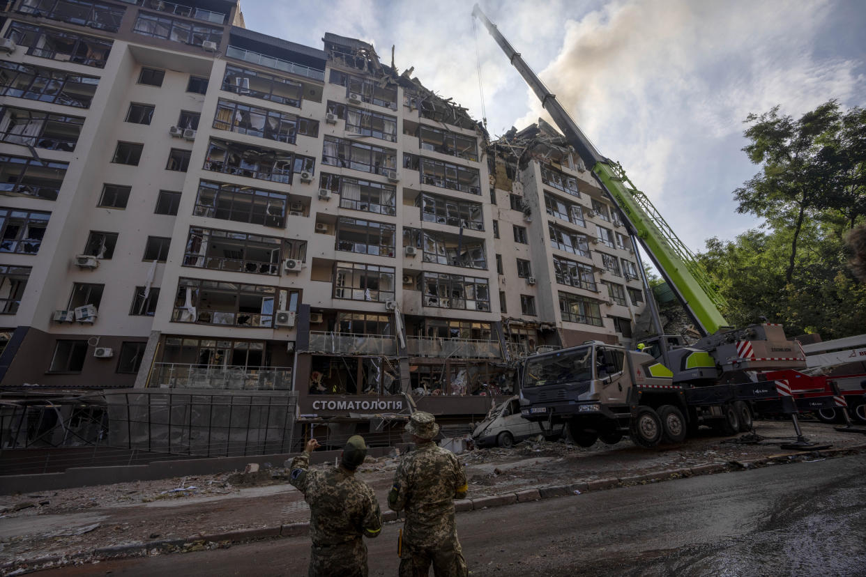 Servicemen work at the scene of a residential building following explosions, in Kyiv, Ukraine, Sunday, June 26, 2022. Several explosions rocked the west of the Ukrainian capital in the early hours of Sunday morning, with at least two residential buildings struck, according to Kyiv mayor Vitali Klitschko. (AP Photo/Nariman El-Mofty)