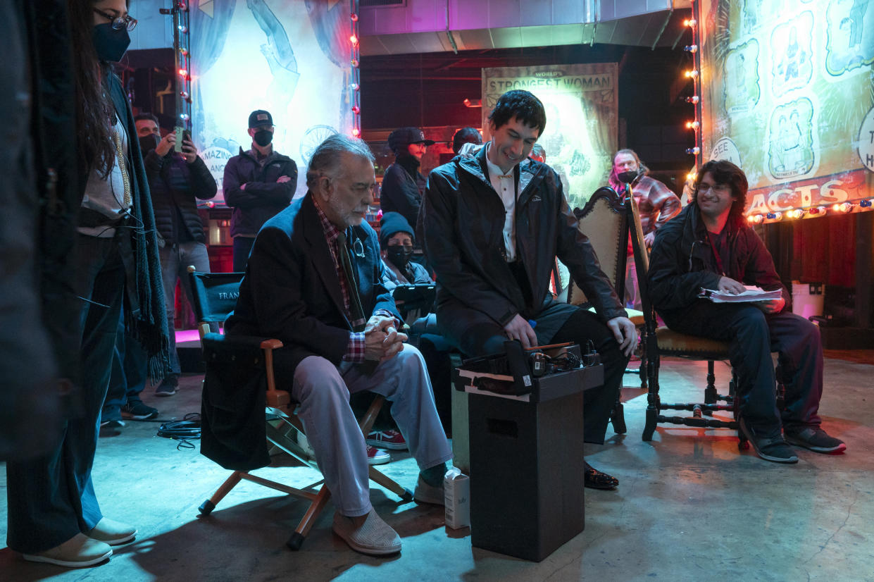 Francis Ford Coppola and Adam Driver sit on chairs near a half dozen other people.