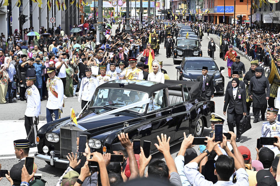 In this photo released by Brunei's Information Department, Brunei's Prince Abdul Mateen and bride Anisha Rosnah, in their car, attend the wedding procession in Bandar Seri Begawan, Brunei Sunday, Jan. 14, 2024. (Brunei's Information Department via AP)