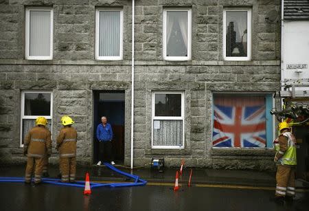 Firefighters pump water from a building following flooding at Newton Stewart in Scotland, Britain December 31, 2015. REUTERS/Darren Staples