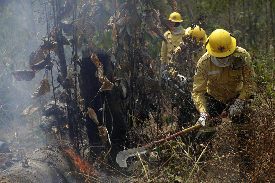 Firefighters work to put out fires in the Vila Nova Samuel region, along the road to the National Forest of Jacunda, near to the city of Porto Velho, Rondonia state, part of Brazil's Amazon, Sunday, Aug. 25, 2019. Leaders of the Group of Seven nations said Sunday they were preparing to help Brazil fight the fires burning across the Amazon rainforest and repair the damage even as tens of thousands of soldiers were being deployed to fight the blazes that have caused global alarm. (AP Photo/Eraldo Peres)