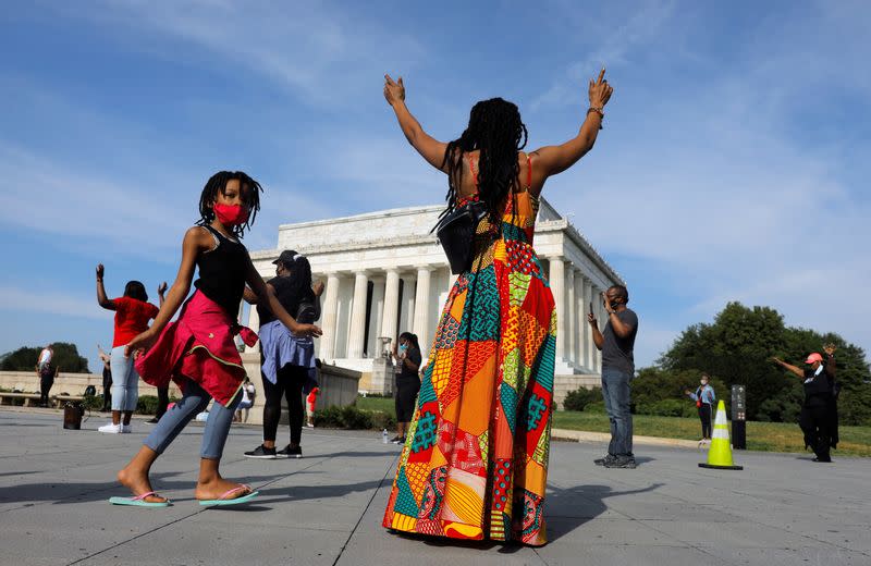 Gente levanta las manos cerca del Monumento a Abraham Lincoln antes de una protesta contra la desigualdad racial tras la muerte de George Floyd bajo custodia policial en Mineápolis, en Washington