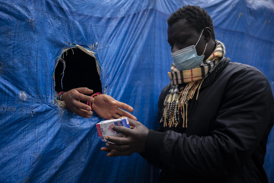 A migrant receives donated food outside Las Raices camp in San Cristobal de la Laguna, in the Canary Island of Tenerife, Spain, Saturday, March 20, 2021. While Spain has been critical of its European neighbours' lack of solidarity when it comes to sharing the responsibility of migration, the country is similarly being criticized by migrants, authorities and human rights organizations on the Canary Islands where some 23,000 people arrived by sea last year and where many thousands remain on the island forcefully. (AP Photo/Joan Mateu)