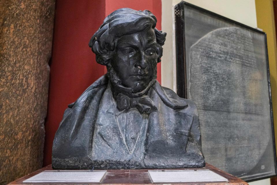 This October 27, 2021 photo shows the bust of French scholar and philologist Jean-François Champollion, known for his decipherment of the Egyptian Hieroglyphic script, in front of a replica of the Rosetta Stone, which was instrumental in the decipherment, on display at the entrance of the Egyptian Museum in Egypt's capital Cairo. / Credit: AMIR MAKAR/AFP/Getty