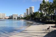 A man sits on a nearly empty Waikiki Beach in Honolulu, Friday, Oct. 2, 2020. After a summer marked by a surge of coronavirus cases in Hawaii, officials plan to reboot the tourism based economy later this month despite concerns about the state's pre-travel testing program. (AP Photo/Caleb Jones)