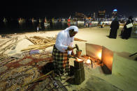 A fisherman works on a tool at Katara Beach during the World Cup soccer tournament, in Doha, Qatar, Thursday, Nov. 24, 2022. (AP Photo/Julio Cortez)