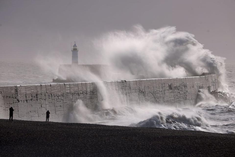 Waves strike a breakwater, with the Newhaven Lighthouse in the background (Getty Images)