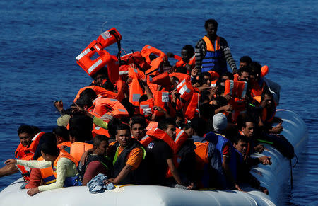 Migrants on a rubber dinghy receive life jackets from rescuers from Malta-based NGO Migrant Offshore Aid Station (MOAS) in central Mediterranean on international waters off Zuwarah, Libya, April 14, 2017. REUTERS/Darrin Zammit Lupi