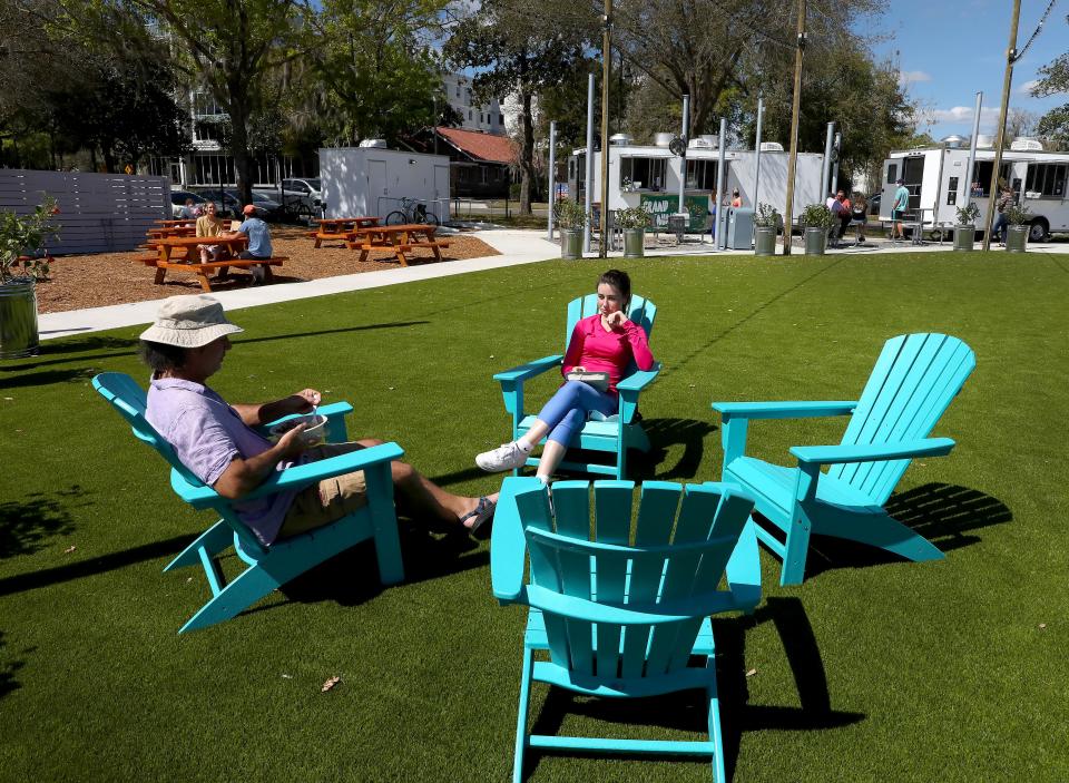 People eat in the Adirondack chairs at the Midpoint Park & Eatery in Innovation Hub area of Gainesville.