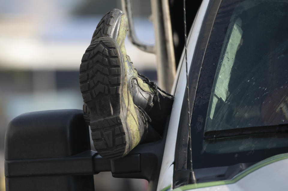 A man rests his feet out his car window as he waits in a long line to fill up with gasoline in Caracas, Venezuela, Thursday, April 2, 2020. Lines at gas stations around the country's capital are getting longer and longer with some citizens saying it was only this bad during the oil worker's strike of 2002. (AP Photo/Ariana Cubillos)