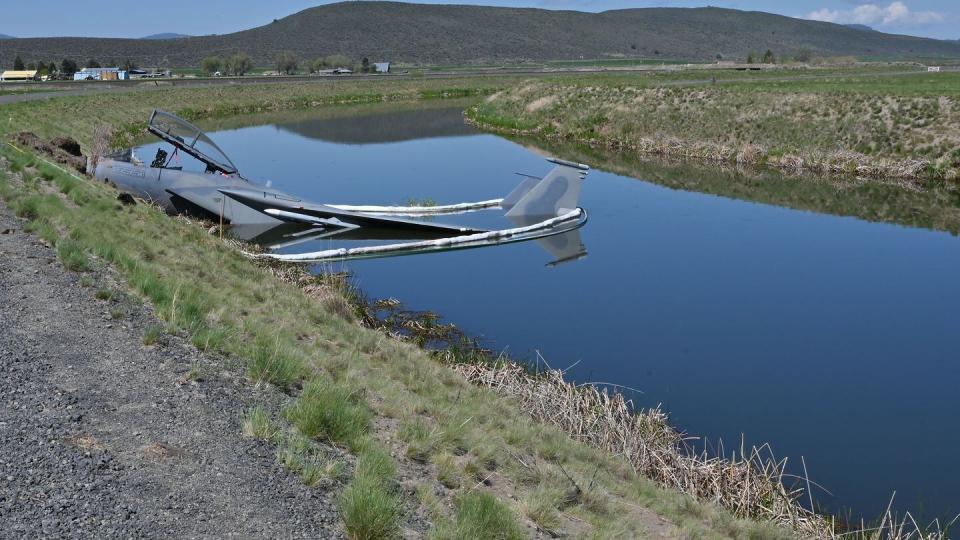 A U.S. Air Force F-15D assigned to the 173rd Fighter Wing sits in a Bureau of Reclamation canal on the south side of the runway after a mishap at Kingsley Field in Klamath Falls, Oregon, May 15, 2023. Absorbent booms surround the aircraft as precaution against the leakage of fuel or other substances. (Master Sgt. Jefferson Thompson/Air National Guard)