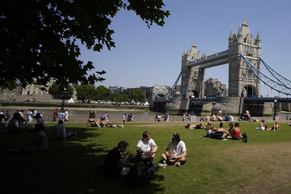 People sit and lie in the sun and shade backdropped by Tower Bridge, during hot weather in London, Monday, July 18, 2022. Britain's first-ever extreme heat warning is in effect for large parts of England as hot, dry weather that has scorched mainland Europe for the past week moves north, disrupting travel, health care and schools. (AP Photo/Matt Dunham)