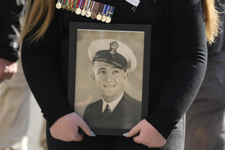 Amelia Walker carries a photo and wears the medals of her great-grandfather, WWII veteran Ross Walker, during the Anzac Day parade in Sydney, Tuesday, April 25, 2023. (AP Photo/Rick Rycroft)