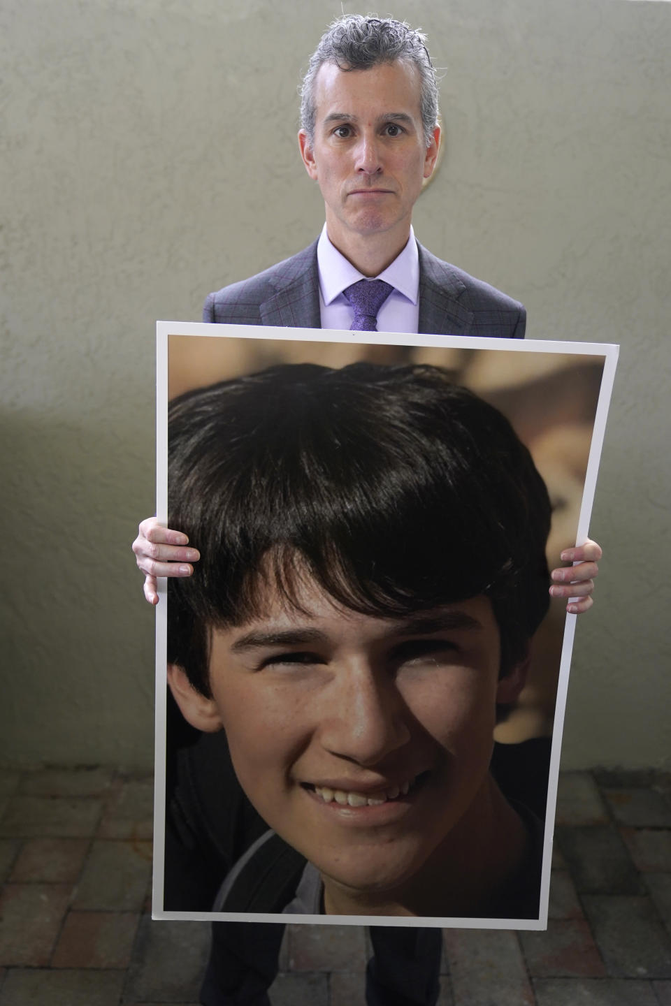 Max Schachter holds a photo of his son, Alex, during an interview, Monday, Jan. 30, 2023, at his home in Coral Springs, Fla. After Alex was killed at Parkland's Marjory Stoneman Douglas High School shooting five years ago, Schachter ended his insurance practice and made promoting school safety his full-time mission. He started Safe Schools for Alex. The foundation's website also has a dashboard where parents in several states can examine safety data for their child's school. (AP Photo/Wilfredo Lee)